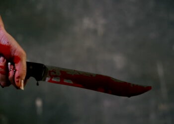 Bloody hand holding up a knife (archives)