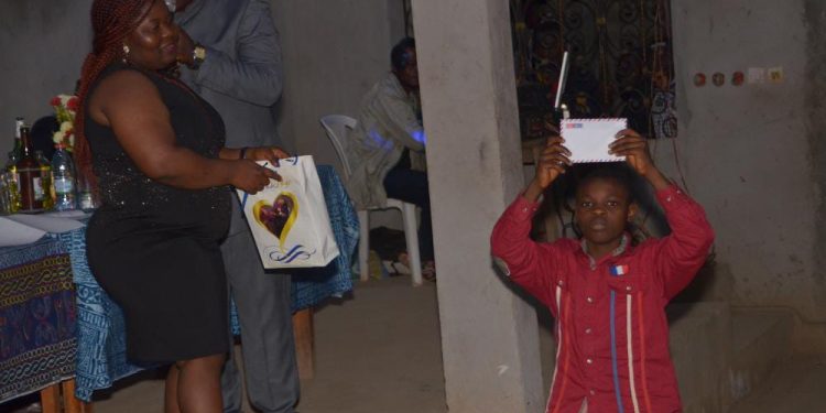 One of the beneficiaries presenting his envelope to the Kejom community