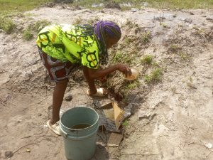 A young girl cleans a puddle from where residents fetch water to drink